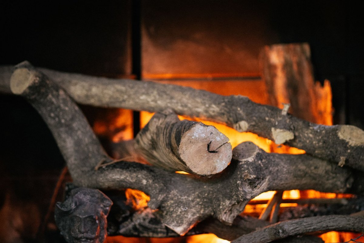 leña seca apilada junto a chimenea encendida en cabaña